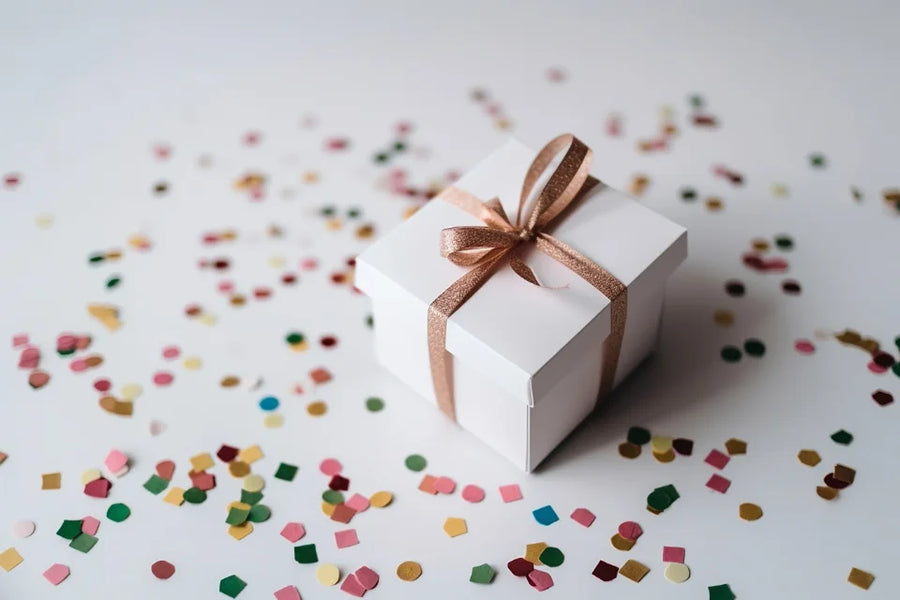 A wrapped gift box with a ribbon among party confetti