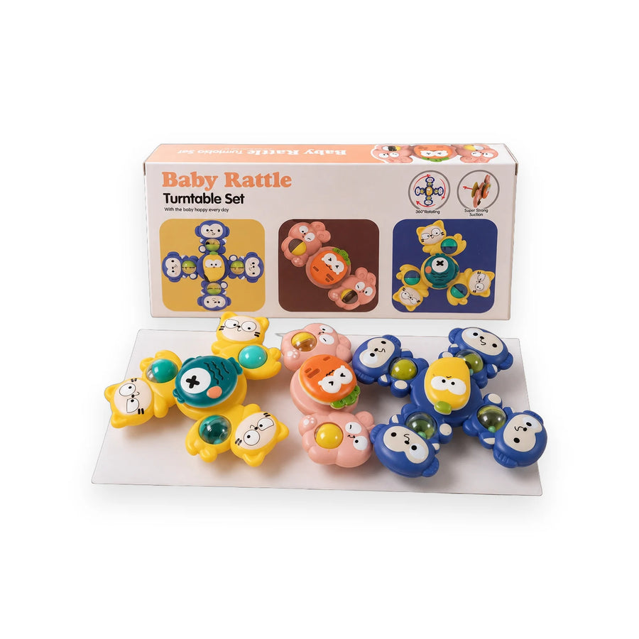 Three Little Tin Lok spinning baby rattles in blue, pink and yellow beside their box