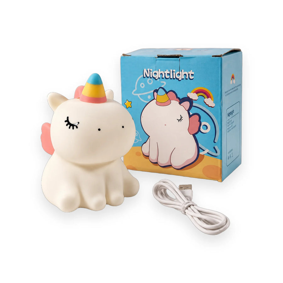 White squishy unicorn night light with a rainbow horn and closed eyes beside its blue box